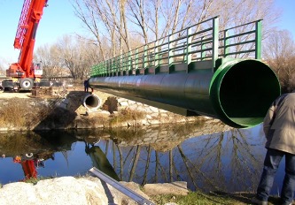 Grúa y a su derecha un colector general de aguas residuales verde